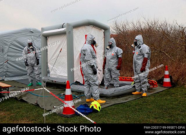 17 March 2023, Lower Saxony, Wangerooge: Emergency personnel in protective suits stand at a decontamination tent during a large-scale exercise of the emergency...