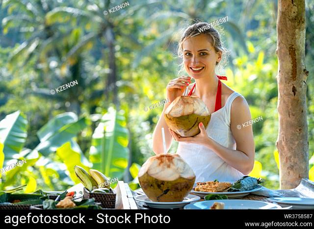 Woman in jungle gazebo sipping on a coconut and eating exotic foods
