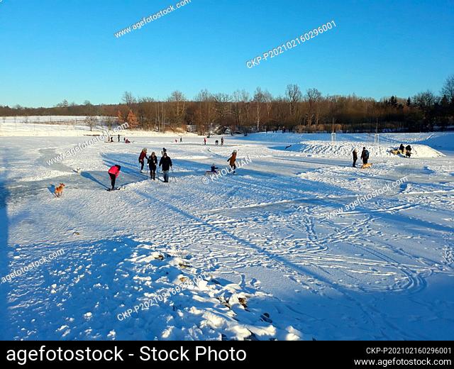 People enjoy the sunny wintry weather and winter sports on the frozen pond Rozpakov in Ricany, Czech Republic, February 15, 2021