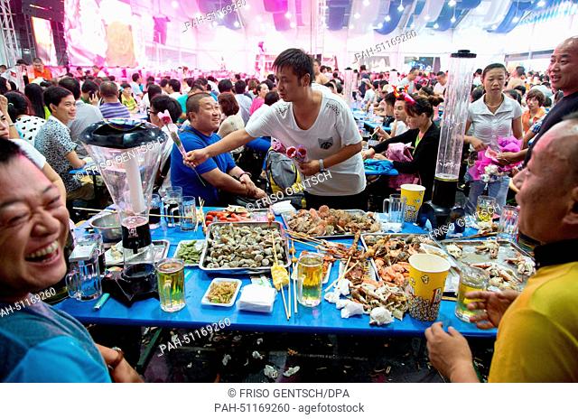 People eat seafood during 24th Oktoberfest in Qingdao, China, 16 August 2014. According to organizers, it is the largest beer festival in Asia