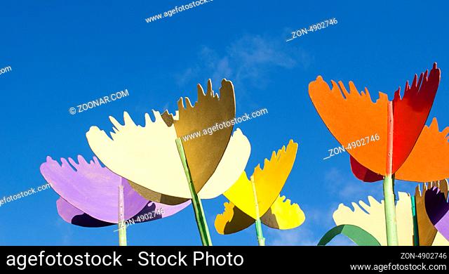 colorful stylized design decor tulips cut from plywood wood board against blue sky background