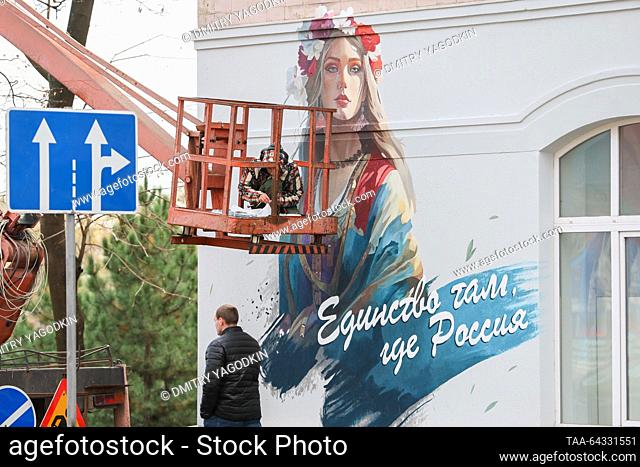 RUSSIA, DONETSK - NOVEMBER 3, 2023: A man walks past a graffiti painted by artist Vladislav Stepnoi on a building wall to mark Russia's National Unity Day