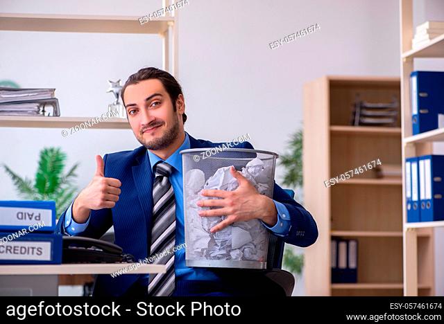Young male employee rejecting new ideas with lots of papers in the basket