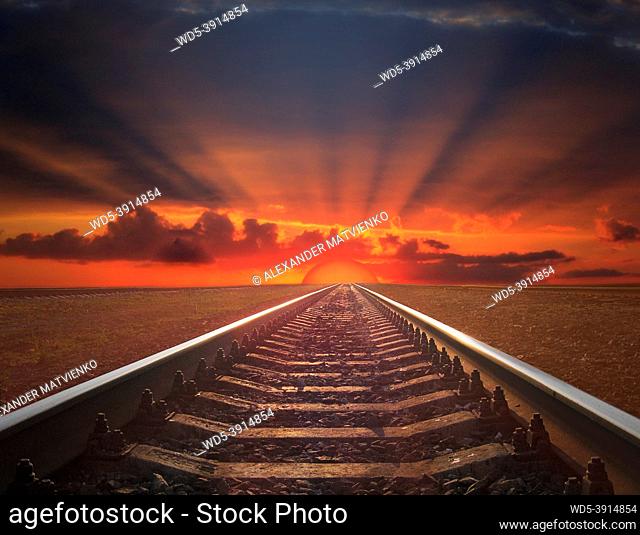 rails going away into the fiery red sunset. rails going away into the dark landscape with fiery red sunset