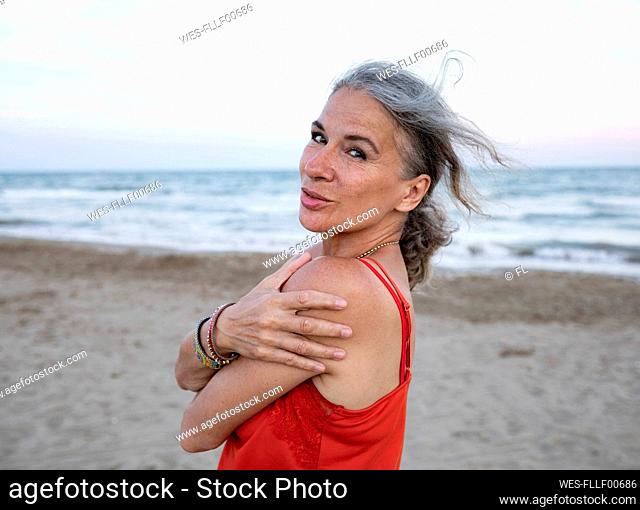 Senior woman hugging self at beach