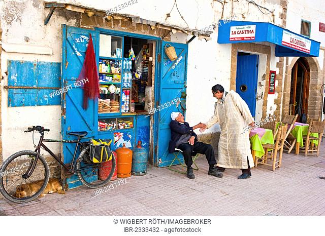 Two men greeting each other in front of a small shop, Essaouira, Morocco, Africa