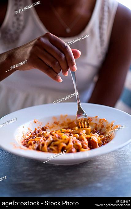 young beautiful African American woman enjoys while eating delicious pasta