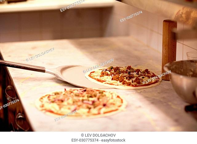 food, italian kitchen, culinary, baking and cooking concept - peel taking pizza off table at pizzeria