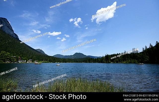 13 August 2021, Bavaria, Hintersee: Excursionists with boats are on the way on the Hintersee. The mountain lake lies at over 789 above sea level