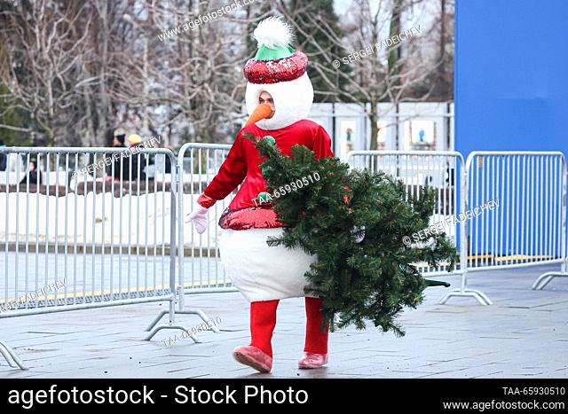 RUSSIA, MOSCOW - 20 de diciembre de 2023: Un intérprete en un traje de muñeco lleva un árbol de Navidad en el callejón principal del centro de exposiciones...