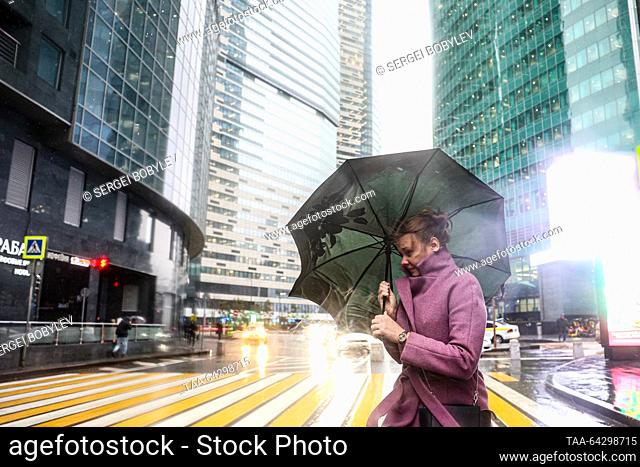 RUSSIA, MOSCOW - NOVEMBER 2, 2023: Women holding umbrellas crosses a street in the rain in the Moscow International Business Centre in late autumn