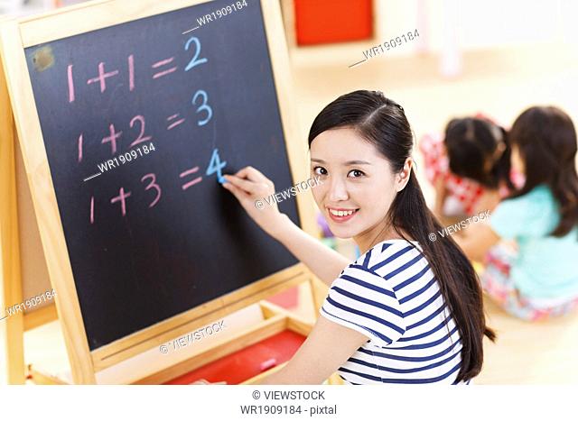 A kindergarten teacher was writing on the blackboard