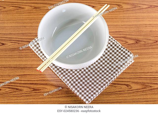 white bowl and chopstick with kitchen towel on wood background