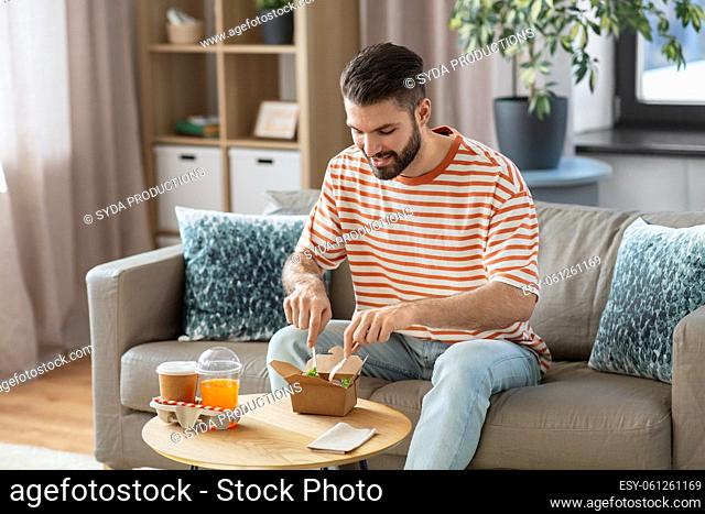 smiling man eating takeaway food at home