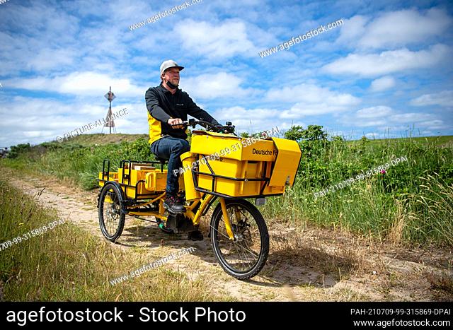 24 June 2021, Lower Saxony, Baltrum: Andre Krandick, postman, distributes letters and parcels on the East Frisian island of Baltrum