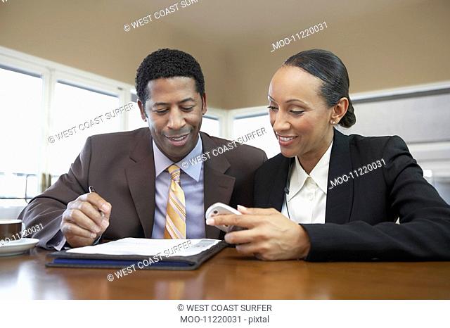 Businessman and Businesswoman with file and cell phone in office