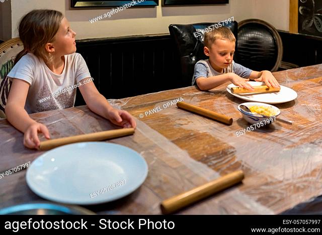 Picture of kids playing with wooden stick on the table while waiting for dumpling making class session to start