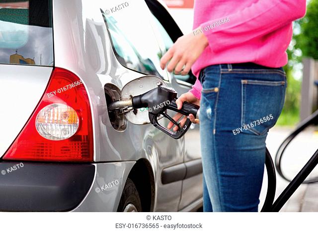 Closeup of woman pumping gasoline fuel in car at gas station. Petrol or gasoline being pumped into a motor vehicle car