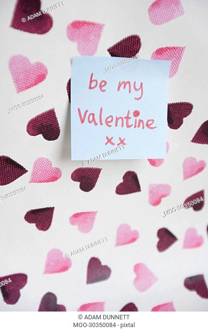 Close-up of sticky note with a orthographic message over heart shaped background