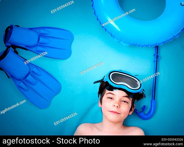 Child lying on blue blanket with swimming mask and flippers