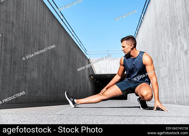 man doing sports and stretching leg outdoors