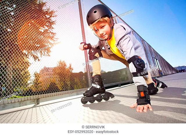 Close-up portrait of preteen boy, roller skater in protective gear, posing on floor at outdoor rollerdrom