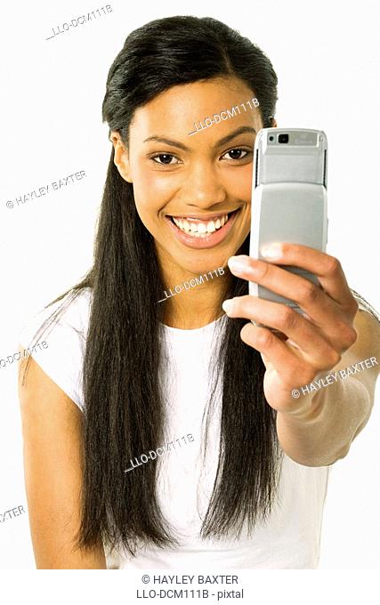 Studio shot of Young girl taking picture using mobile phone