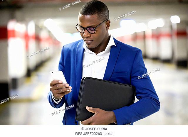 Young businessman wearing blue suit jacket and using smartphone