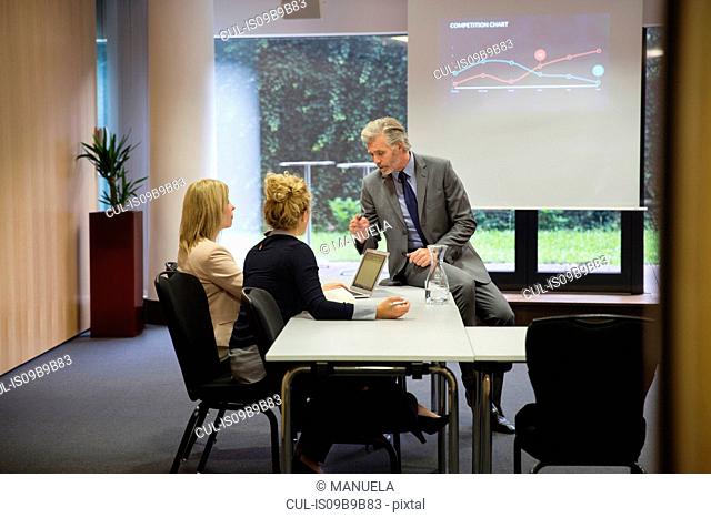 Colleagues in conference room, presentation on projection screen