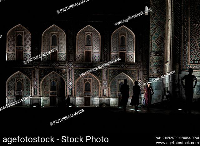 26 September 2021, Uzbekistan, Samarkand: Uzbeks walk at the historical landmark of Registan in Samarkand. The Registan was a public square and center of...