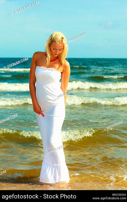 Girl taking walk on shore. Young elegant woman in white dress. Outdoor leisure relax concept