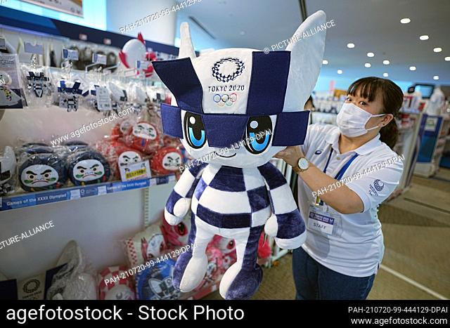 20 July 2021, Japan, Tokio: A saleswoman holds up a cloth figurine of the Olympic mascot Miraitova at an Olympic Games fan shop