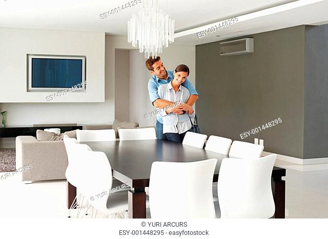 Affectionate couple embracing in their modern dining room
