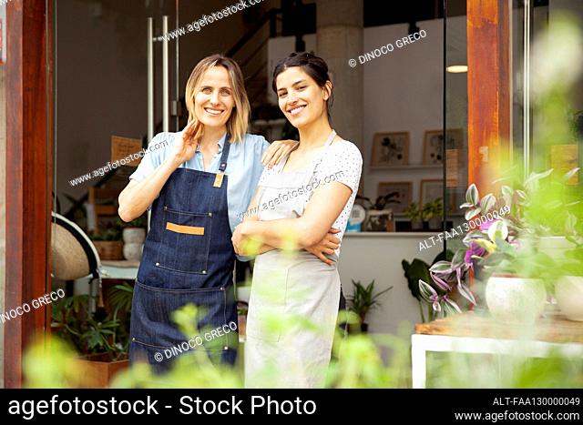 Greenhouse owners wearing apron while standing at store entrance