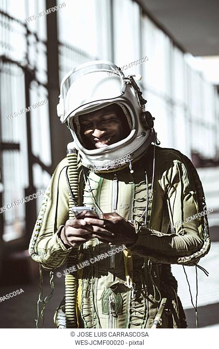 Smiling astronaut in spacesuit using smartphone