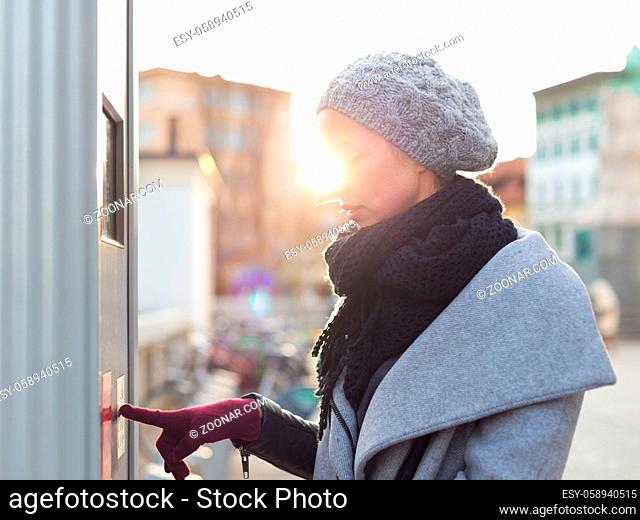 Casual woman buying public transport tickets on city urban vedning machine on cold winter day in Ljubljana, Slovenia