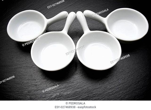 four small white spoons on a table slate