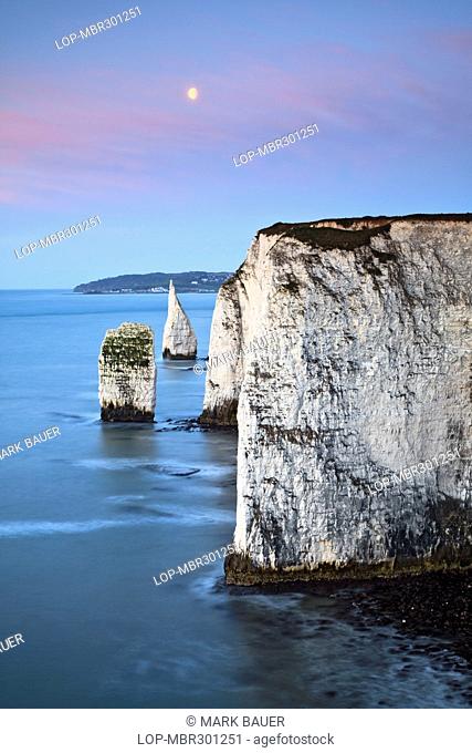 England, Dorset, Swanage. The moon setting over the Pinnacles, at Handfast Point near Swanage