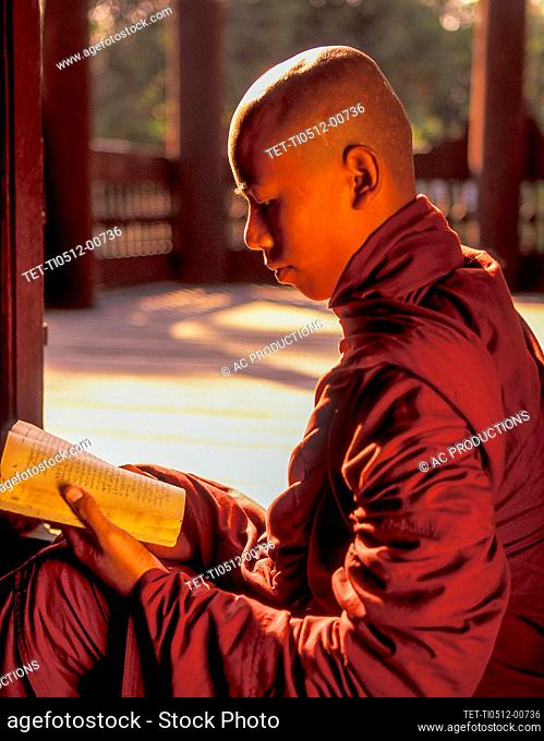 Myanmar, Mandalay, Buddhist monk reading prayers book
