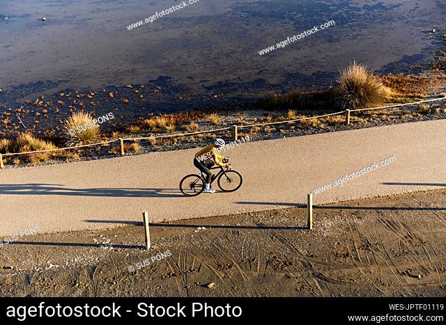Young cyclist riding bicycle by beach on sunny day