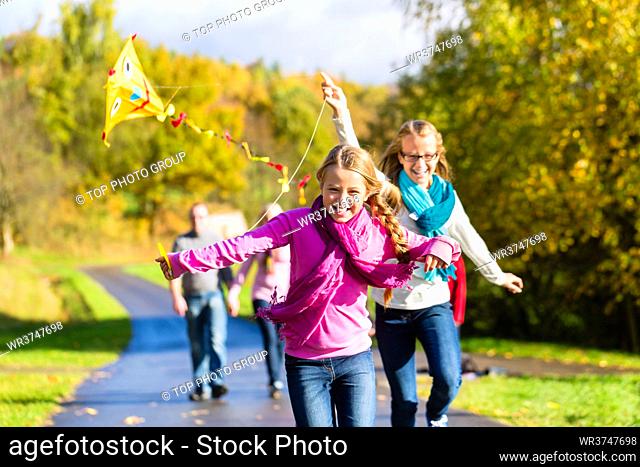 Family take walk in autumn forest flying kite