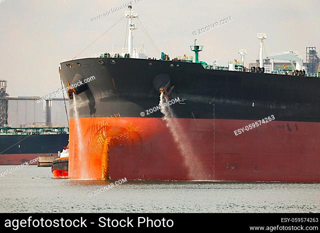 Large crude oil tanker ship pumping out ballast water when coming into port