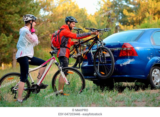 Young Couple Unmounting Mountain Bikes from Bike Rack on the Car. Adventure and Family Travel Concept