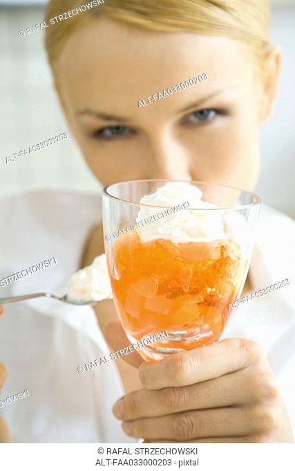 Woman holding up fruit dessert, looking at camera