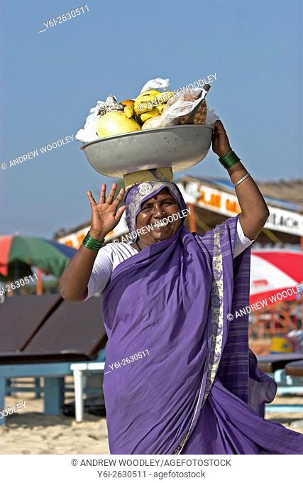 Smiling woman in sari selling fruit from bowl carried on her head Cavelossim Beach Goa India