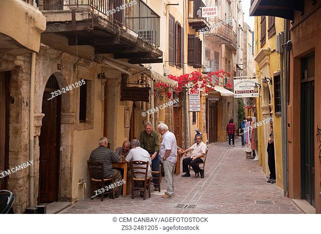 Street scene from the old town with people playing backgammon in the foreground, Chania, Crete, Greek Islands, Greece, Europe