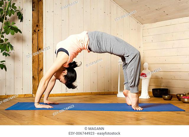 An image of a pretty woman doing yoga at home - Urdhva Dhanurasana