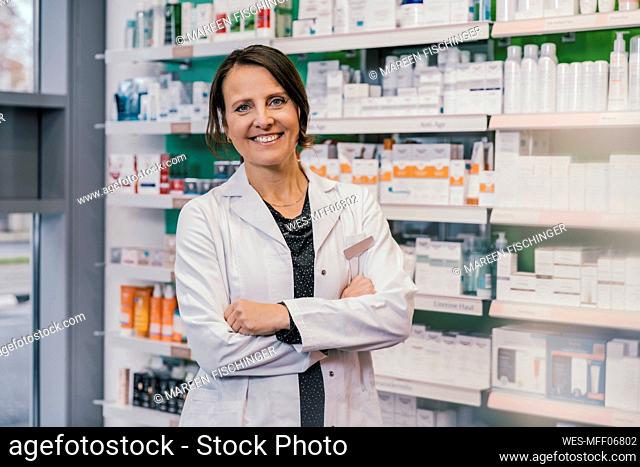 Farmacéutico de sexo femenino confiado con los brazos cruzados en la tienda de la farmacia