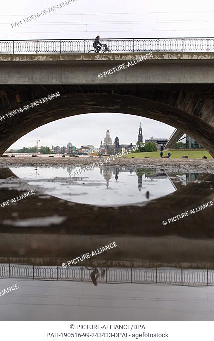 16 May 2019, Saxony, Dresden: The backdrop of Dresden's old town is reflected in a puddle below the Marienbrücke bridge. Photo: Sebastian...