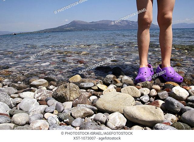 Greece, Thessaly, peninsula Pelion, Concept Holiday image of the legs of a young girl standing in the shallow water of the Mediterranean Sea